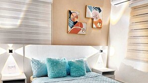 Une chambre à coucher moderne avec un lit, des tables de chevet et des œuvres d’art accrochées au mur.