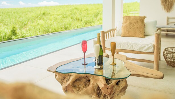 Ein modernes Zimmer mit Glastisch, Pool und Blick auf ein grünes Feld.