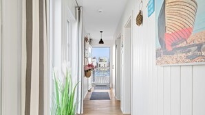 A hallway with a wooden floor, white walls, and a view of a building through an open door. - Sea Breeze: Meerblick, Sauna, Dachterrasse, Bootsanleger (Olpenitz)