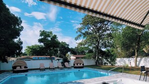 A swimming pool with a hot tub, lounge chairs, and a covered patio area. - Gorgeous Florida Pool and Spa Home (Jacksonville)