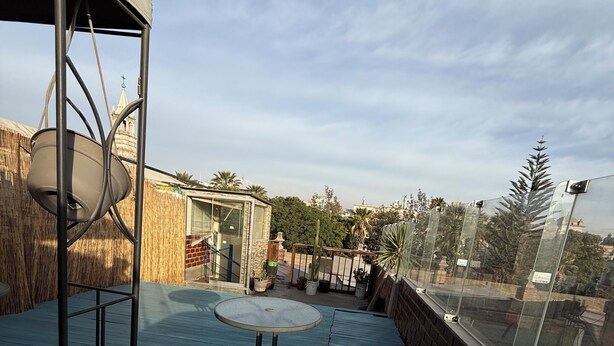 Eine Dachterrasse mit Whirlpool, Tisch und Topfpflanzen.