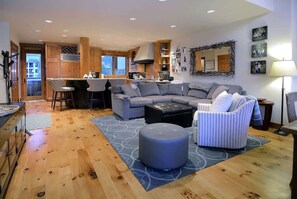 Un salon moderne avec un canapé, un pouf et un coin bar.