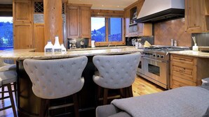 Een keuken met houten kastjes, een groot raam en een bar met barkrukken.