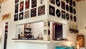 Een keuken met een houten plafond, een barruimte met vinylplaten en een blauwe kruk.