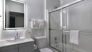 Une salle de bain moderne avec une douche à parois de verre, des toilettes blanches et un meuble-lavabo avec un miroir.