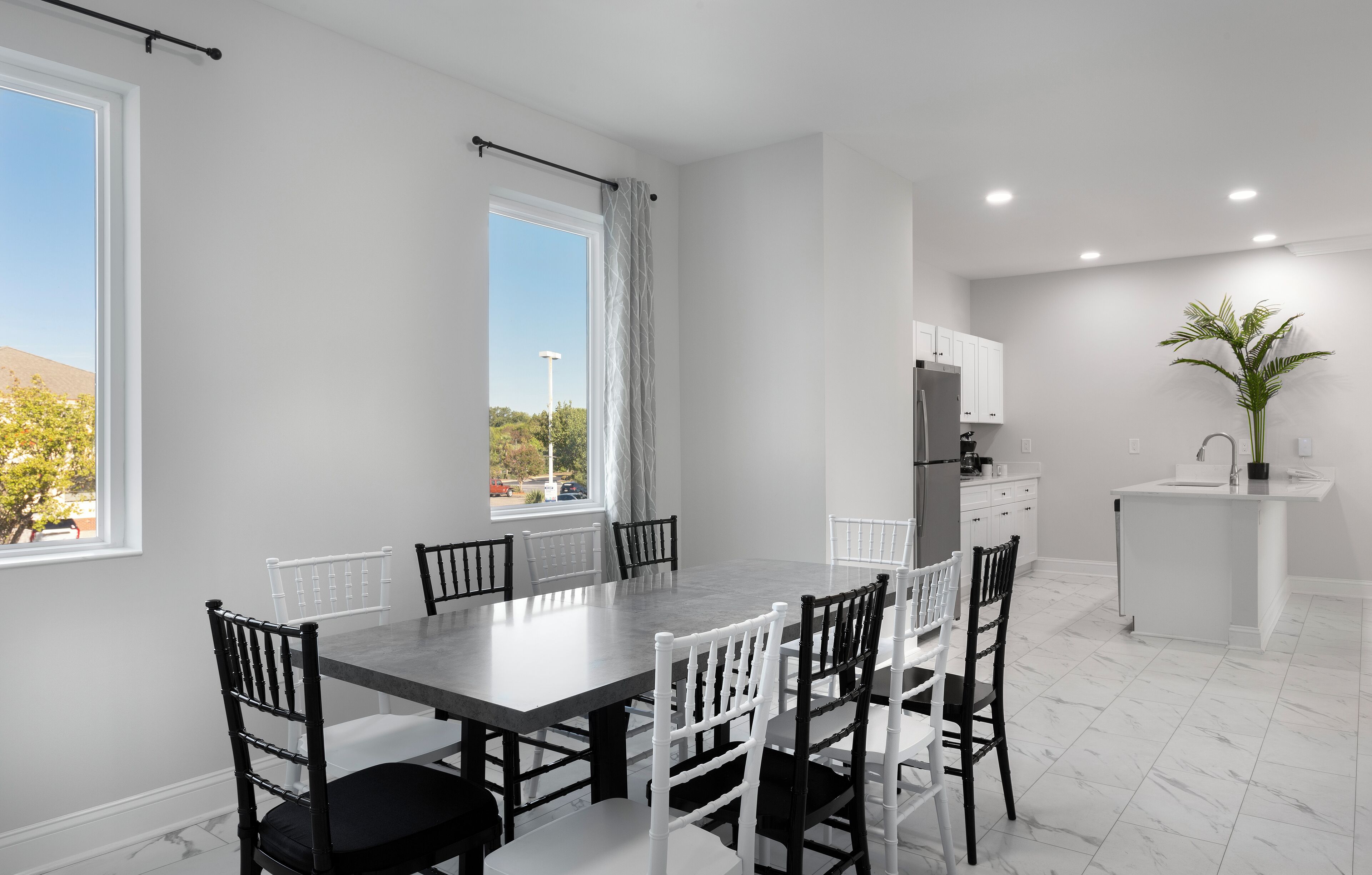 Une cuisine moderne avec des meubles blancs, un îlot central et une vue sur l’extérieur.