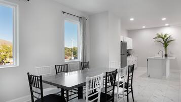 Une cuisine moderne avec des meubles blancs, un îlot central et une vue sur l’extérieur.