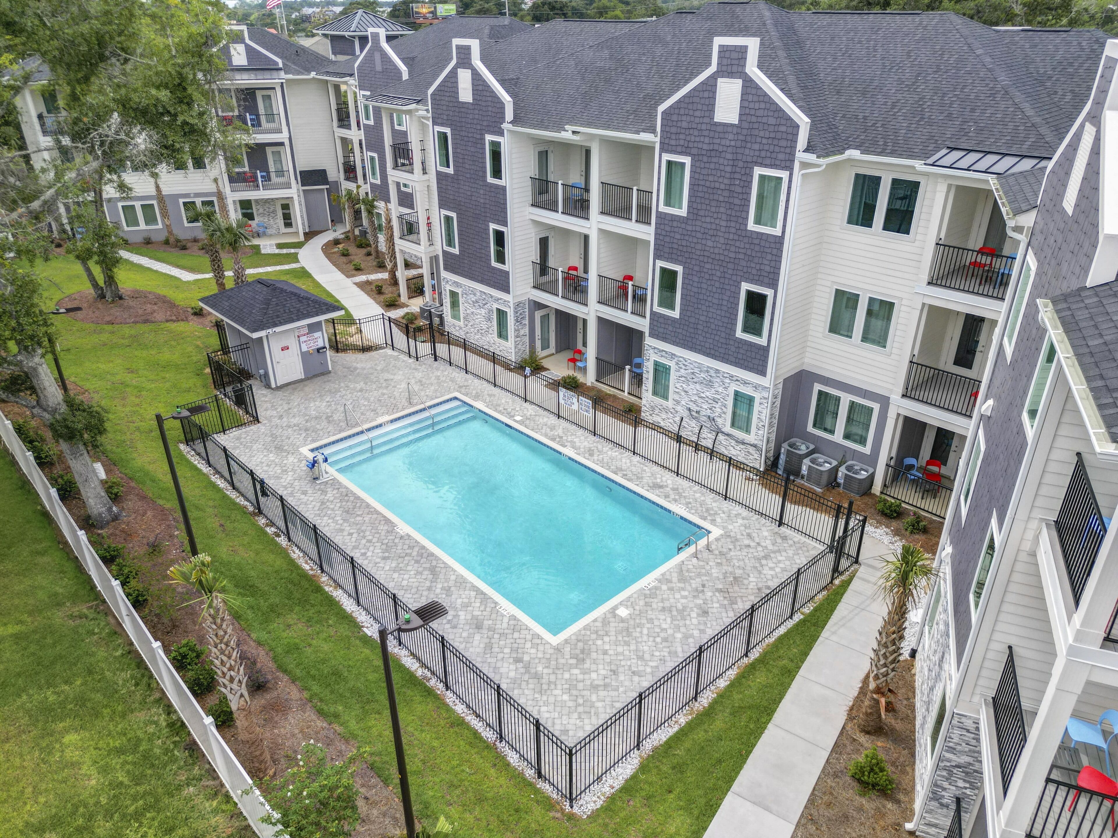 A multi-story residential building with a swimming pool surrounded by a fence.