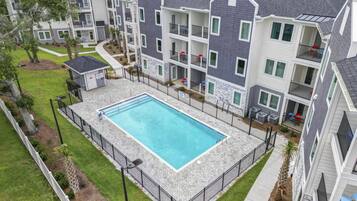 A multi-story residential building with a swimming pool surrounded by a fence.