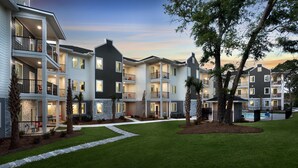 A multi-story residential building with balconies, a swimming pool, and a well-maintained lawn. - Ocean Escape Condos North (North Myrtle Beach)
