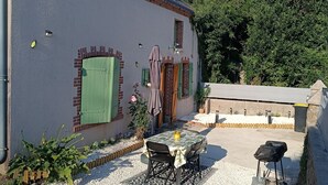 A house with a gravel patio, a table with chairs, and a small garden area.