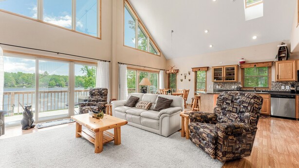 A spacious living room with a large window, a sofa, a patterned armchair, and a wooden coffee table.