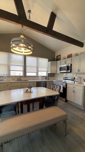 A spacious kitchen with a large island, white cabinetry, and a modern chandelier.