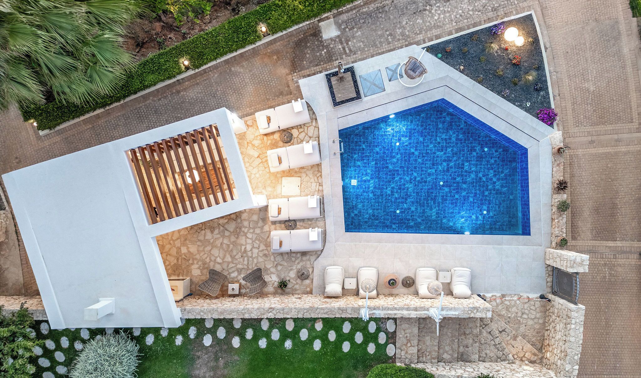 A rooftop pool with a geometric design, surrounded by white lounge chairs and a sun terrace.