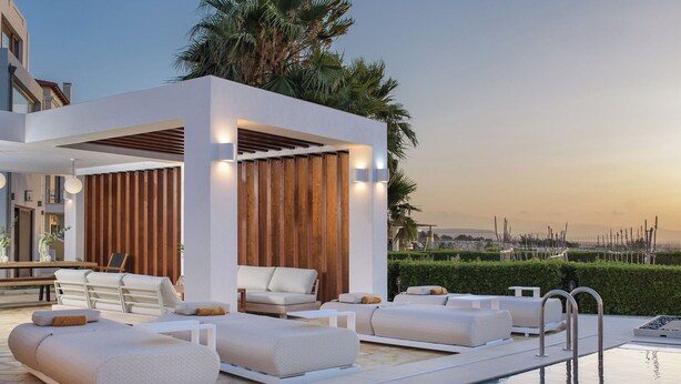 Un espace piscine extérieur moderne, doté de chaises longues et d’une pergola en bois.