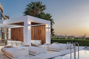 A modern outdoor pool area with lounge chairs and a wooden pergola. - Therros Villa with private pool by Estia (Agios Ioannis)
