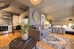 A modern living room with a sofa, a dining area with a table and chairs, a kitchen with an oven, and a large mirror on the wall. - Cultural Gem in the Heart of Central Reykjavík (Reykjavík)