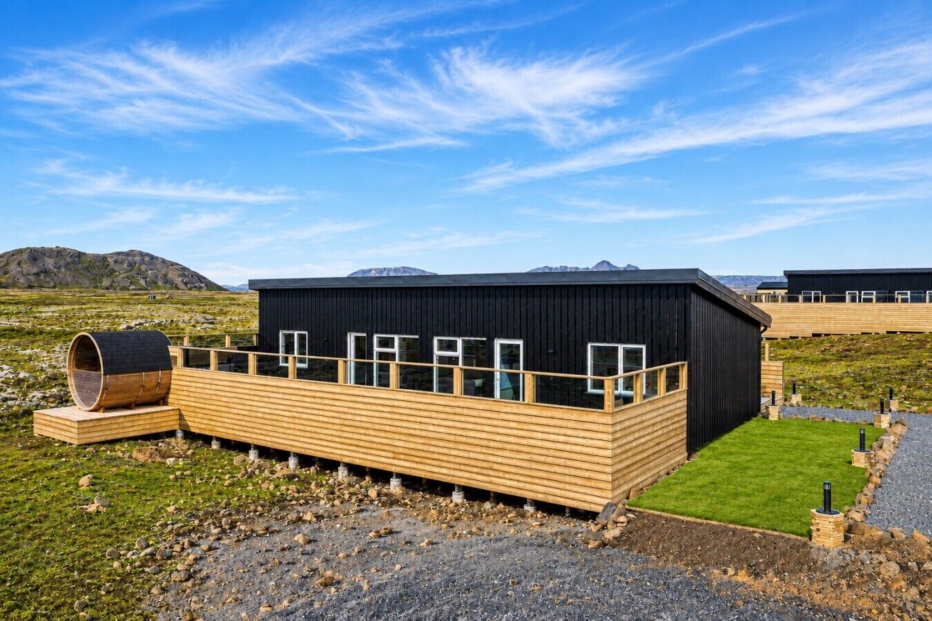 A modern building with a wooden deck, large windows, and a black exterior.
