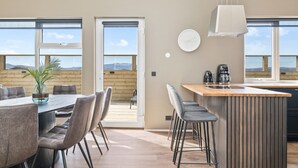 A modern kitchen with a large island, a dining area with chairs, and a view of the mountains through the windows.