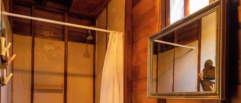Un baño de madera con un espejo grande, un lavamanos blanco y una lámpara colgante.