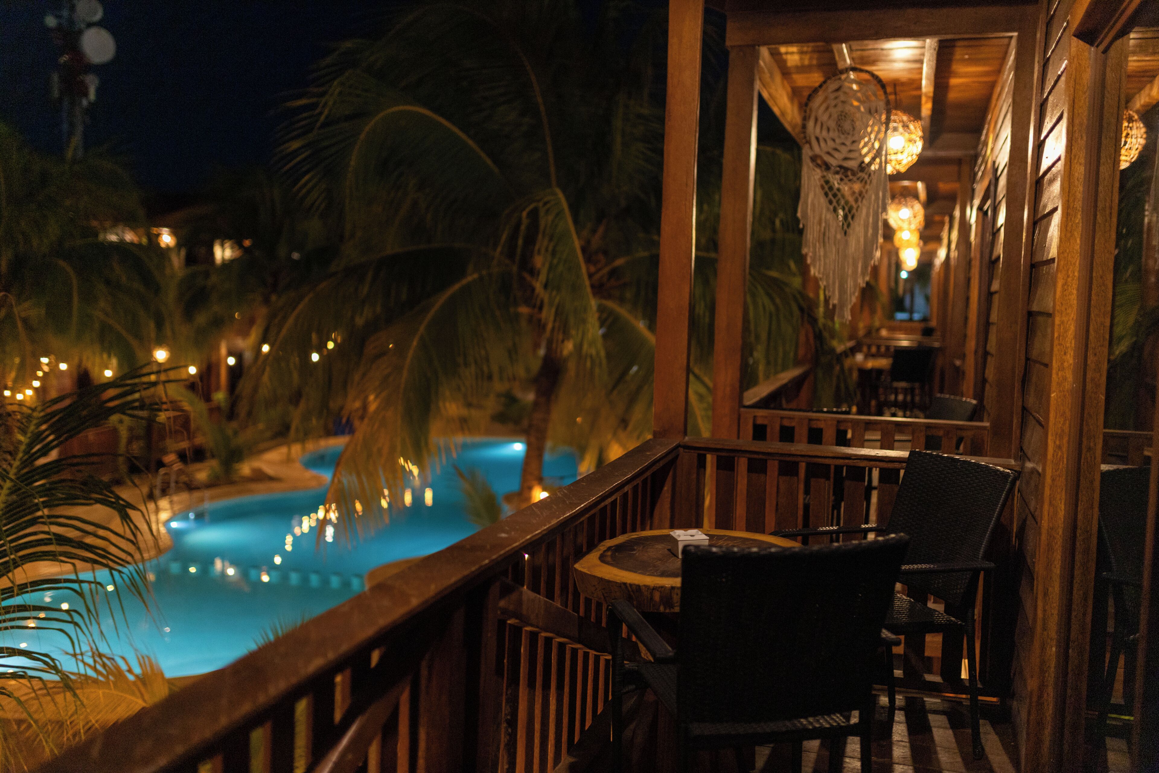 A poolside area with a wooden deck, chairs, and a view of a swimming pool.