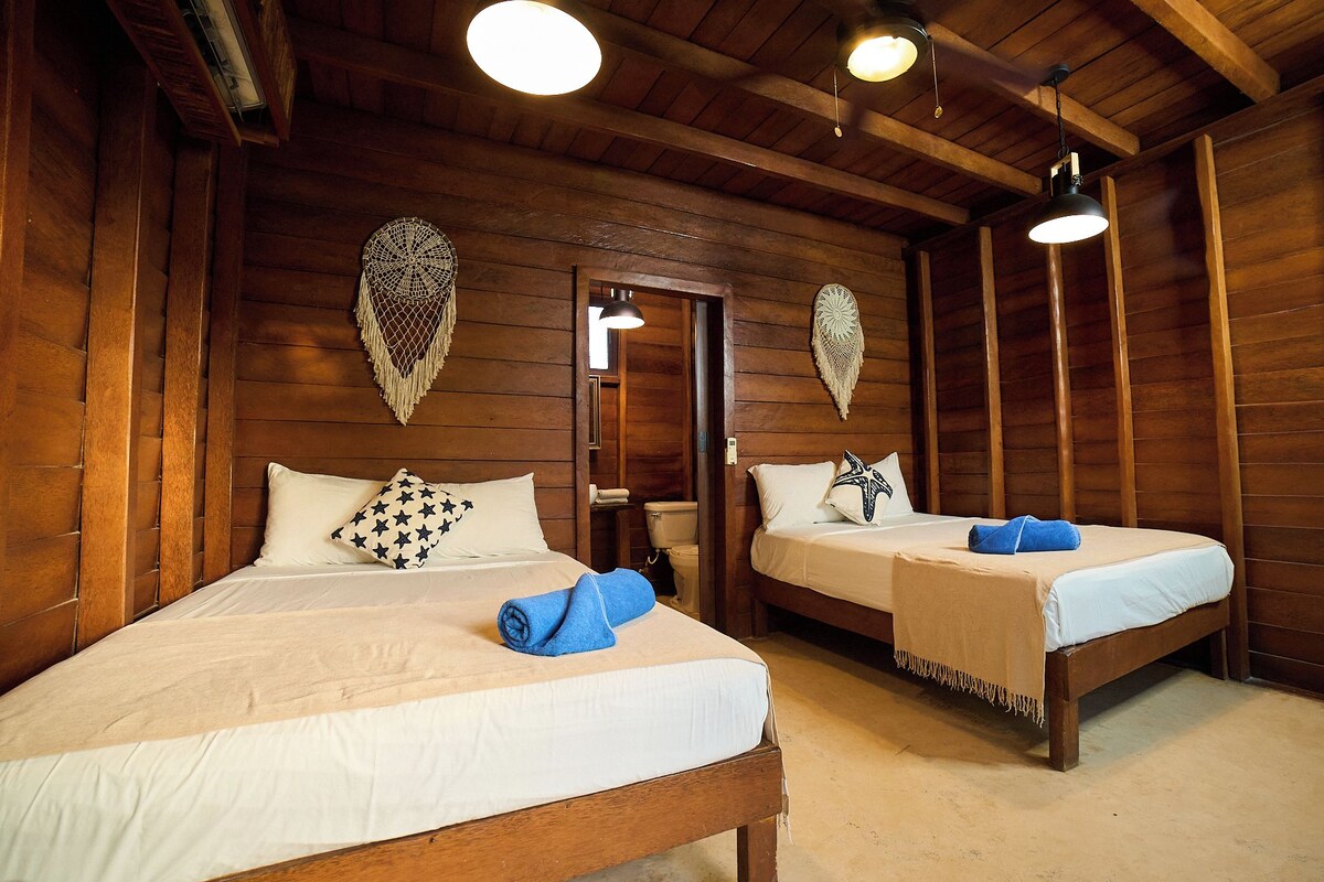 A wooden room with two beds, a door, and wall decorations.