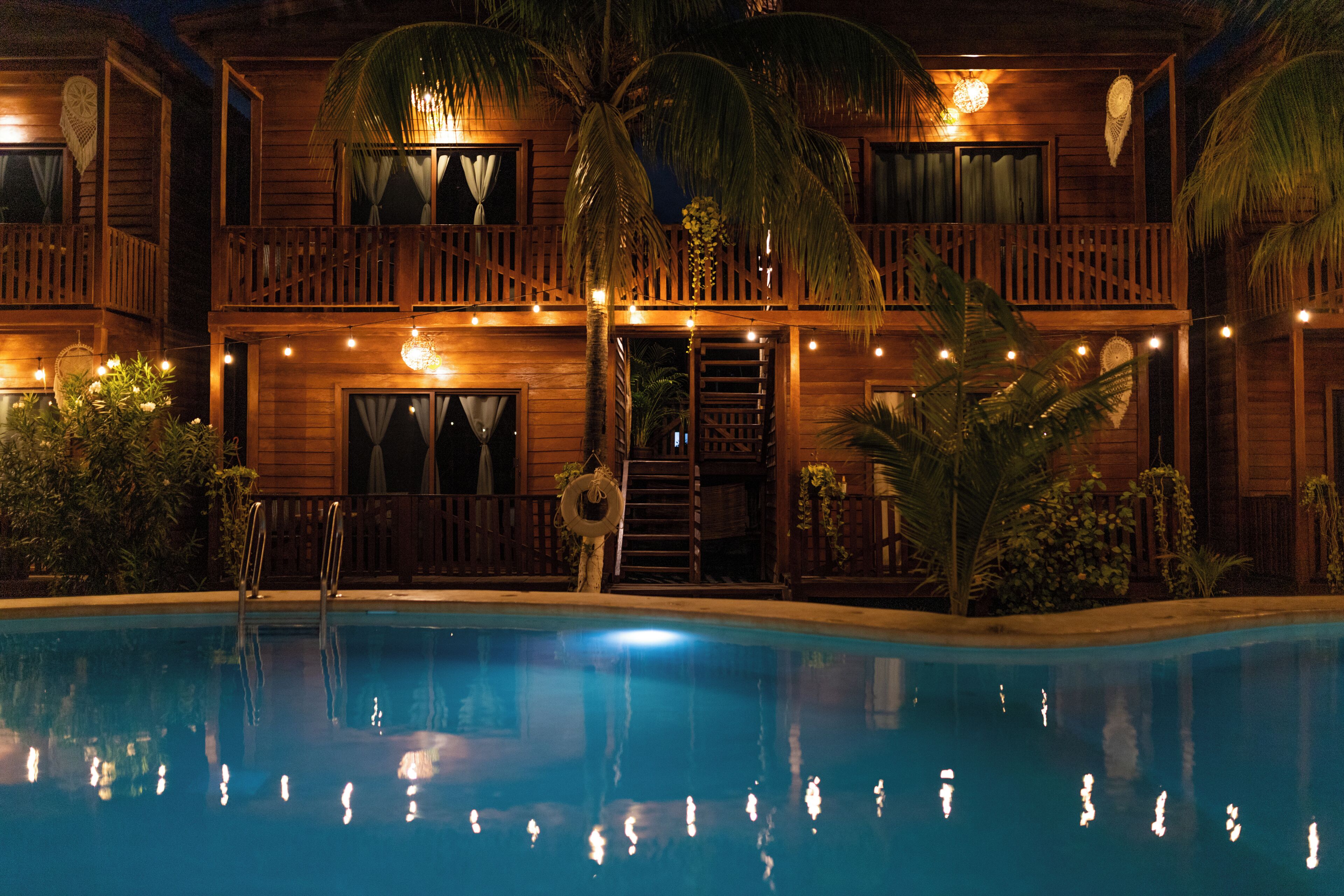 Un edificio de madera con piscina, balcones y luces colgantes.