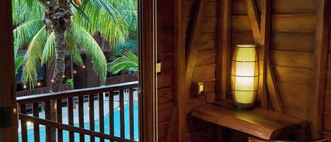 Una habitación de madera con vistas a una piscina y palmeras.