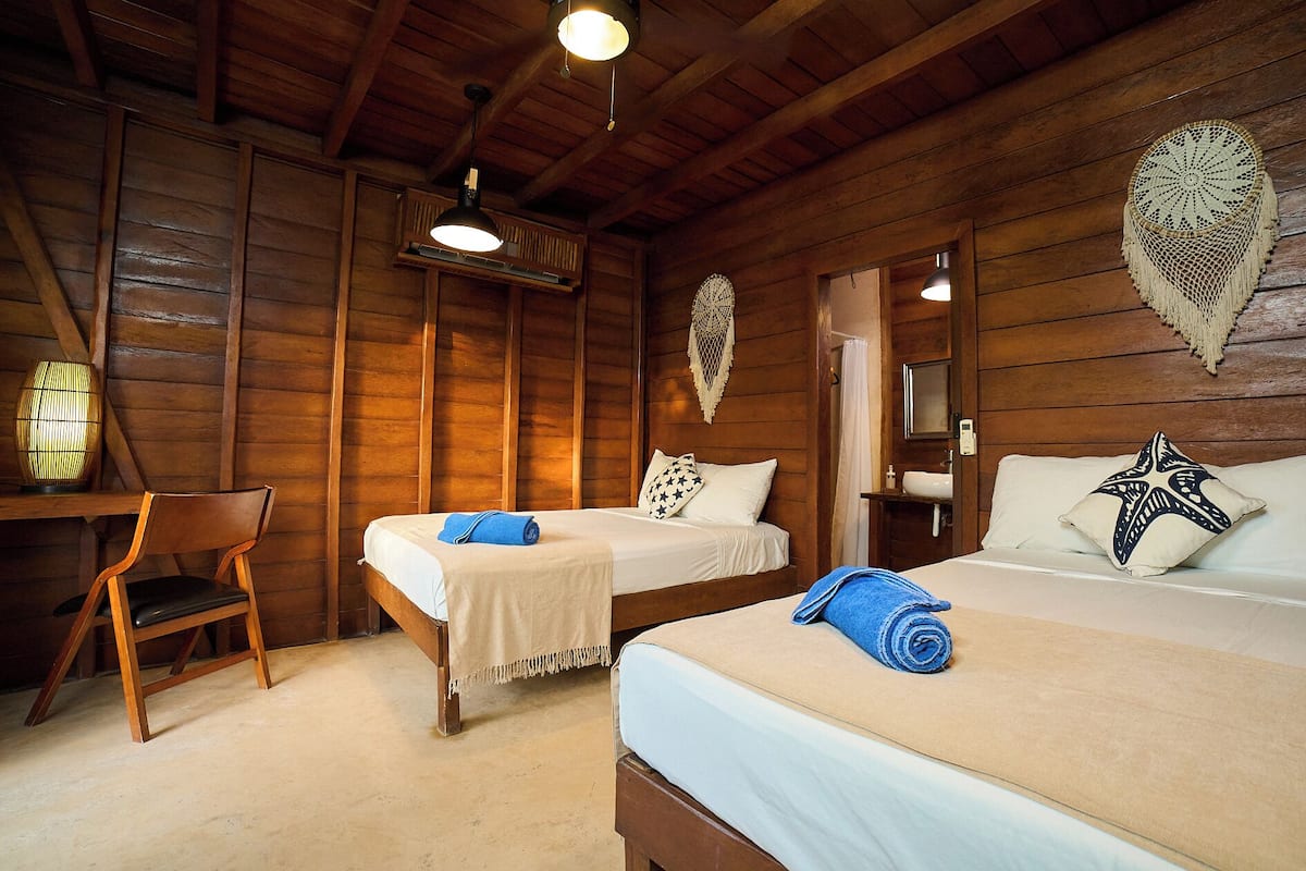 A wooden room with two beds, a desk, and a chair.