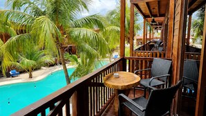 Una terraza de madera con piscina, sillas y una mesa.