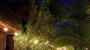 Un sendero bordeado de palmeras y estructuras de madera que conduce a un edificio con terraza de madera.