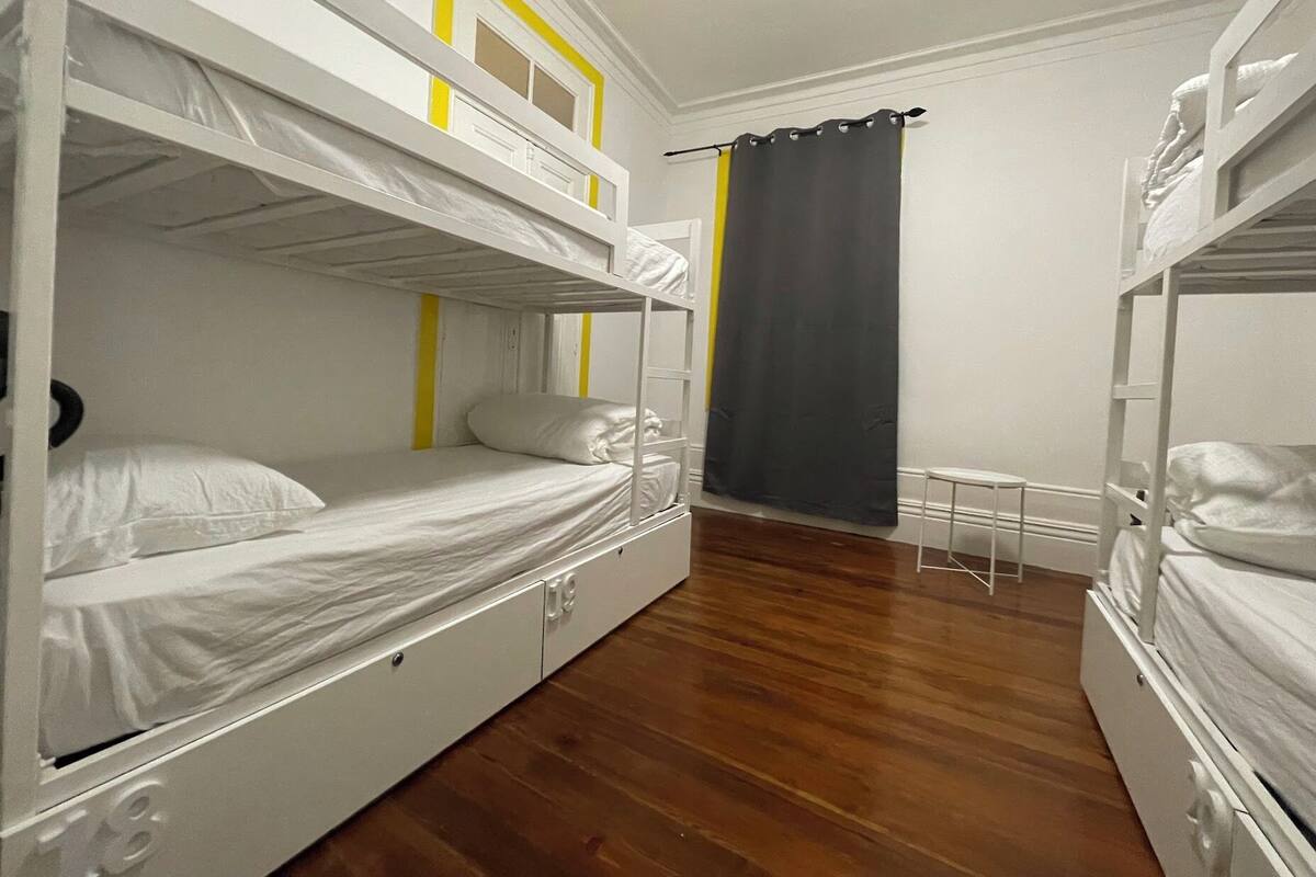 A room with bunk beds, a small table, and a curtain.