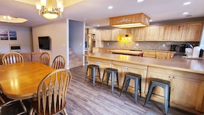 A modern kitchen with wooden cabinets, a central island, and bar stools.