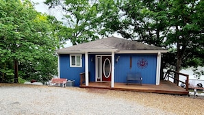 A small, single-story building with a blue exterior, a front porch, and a bench.