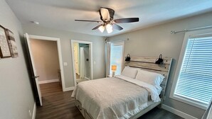 A bedroom with a bed, a ceiling fan, a window with blinds, and a door leading to another room. - Spacious & Modern 2BR Home with Attached Garage (Quincy)