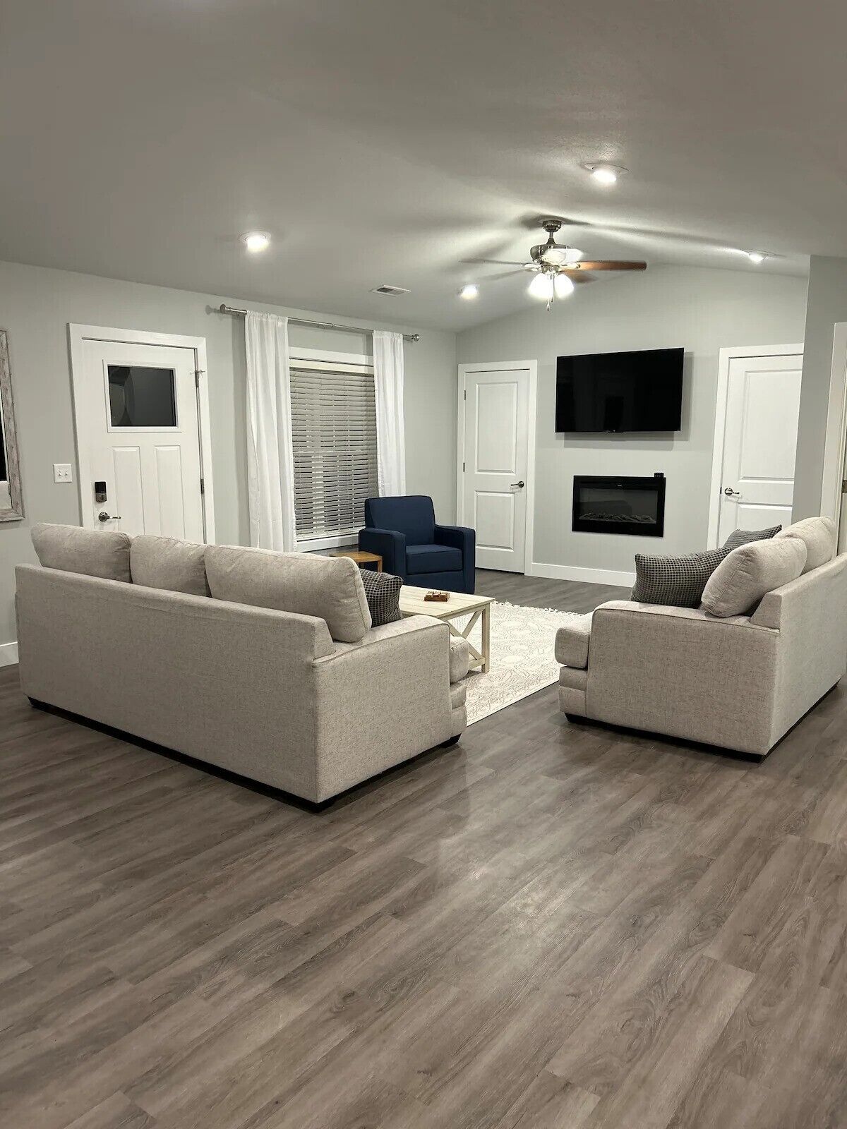 A modern living room with two sofas, a coffee table, a TV, and a fireplace.