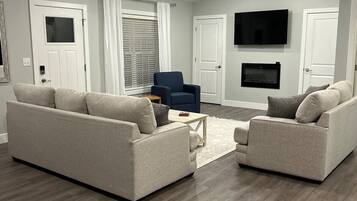 A modern living room with two sofas, a coffee table, a TV, and a fireplace.