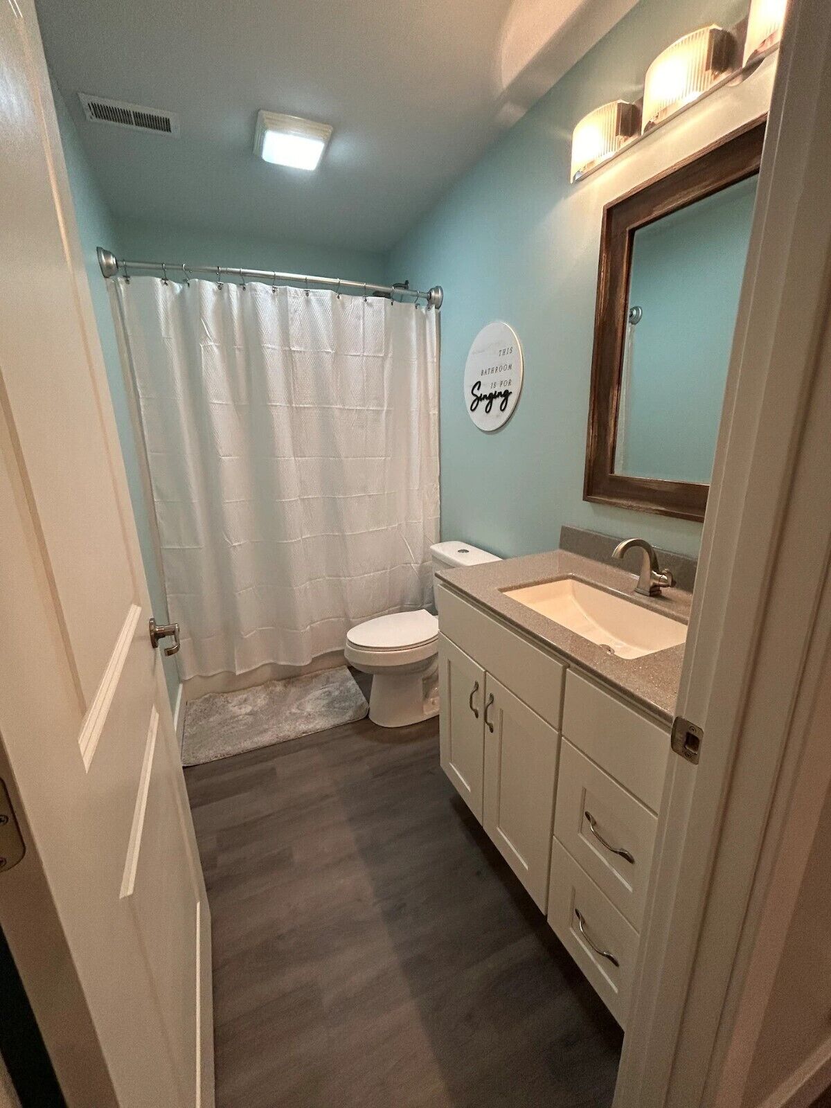 A bathroom with a white toilet, a sink with a mirror above it, and a shower curtain.