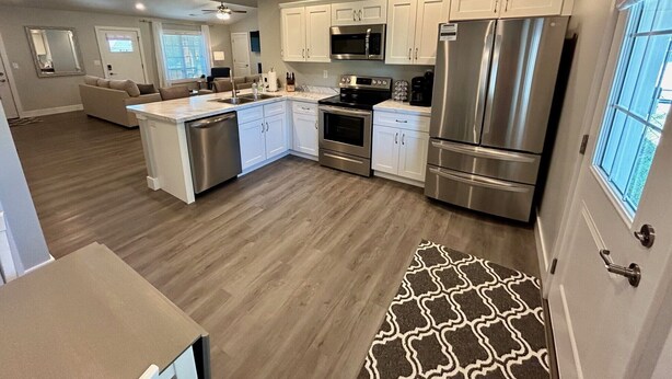 A modern kitchen with white cabinets, stainless steel appliances, and a wooden floor. - Spacious & Modern 2BR Home with Attached Garage (Quincy)