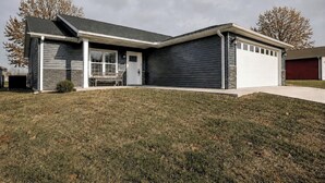 A modern two-story house with a garage, a front porch, and a well-maintained lawn. - Spacious & Modern 2BR Home with Attached Garage (Quincy)