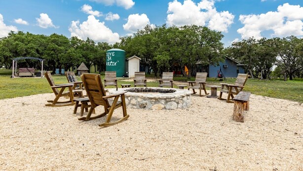 A fire pit area with wooden chairs and a stone fire pit surrounded by a gravel area.