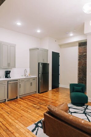 A modern kitchen with grey cabinets, a stainless steel refrigerator, and a coffee maker. - 1 Bedroom Suite (Frankfort)
