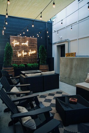 An outdoor seating area with a neon sign, string lights, and a whiskey sign. - 1 Bedroom Suite (Frankfort)
