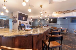 A bar area with a marble countertop, multiple hanging light fixtures, and bar stools. - 1 Bedroom Suite (Frankfort)