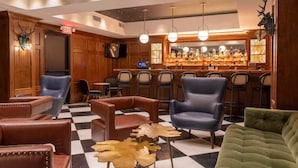 Eine Bar mit Ledersesseln, einem Schachbrettmuster-Boden und einer Theke voller Flaschen.