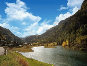 Un río serpentea por un valle, flanqueado por montañas y rodeado de vegetación y algunos edificios.