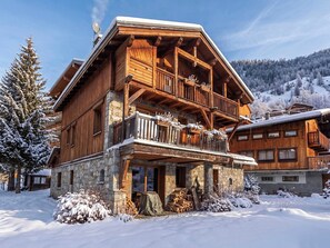 A wooden chalet with a stone foundation, a balcony with railings, and a view of snow-covered mountains. - Casa-Chalet Brizolée avec vue sur le lac à Tignes (Tignes)