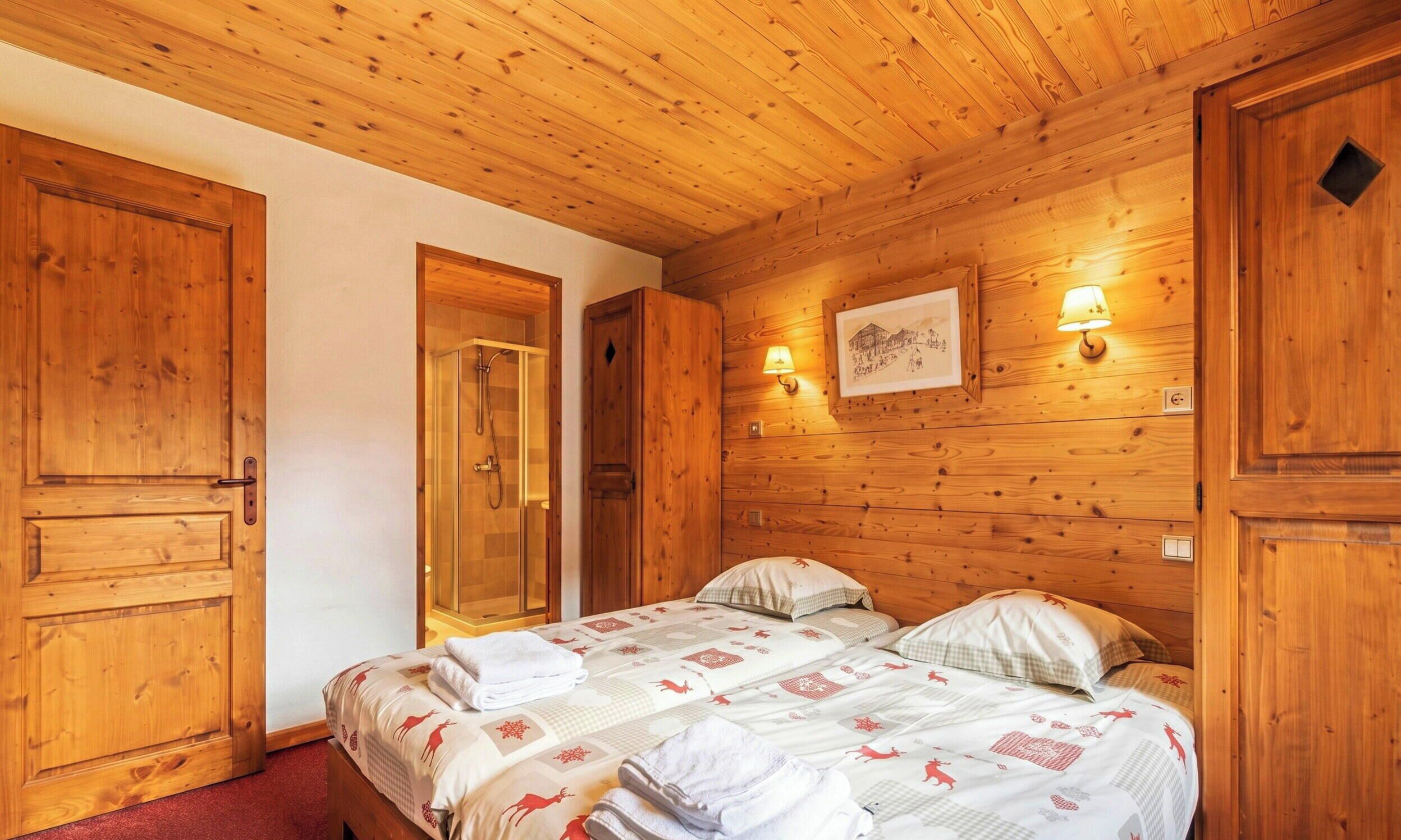 Ein Zimmer mit Holzwandverkleidung, einem Bett, einer Dusche und einer Wandlampe.