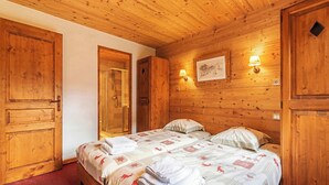 Ein Zimmer mit Holzwandverkleidung, einem Bett, einer Dusche und einer Wandlampe.