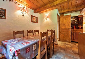 A dining area with a table set for four, wooden chairs, a wall-mounted light fixture, and a wooden cabinet with dishes. - Casa-Chalet Brizolée avec vue sur le lac à Tignes (Tignes)